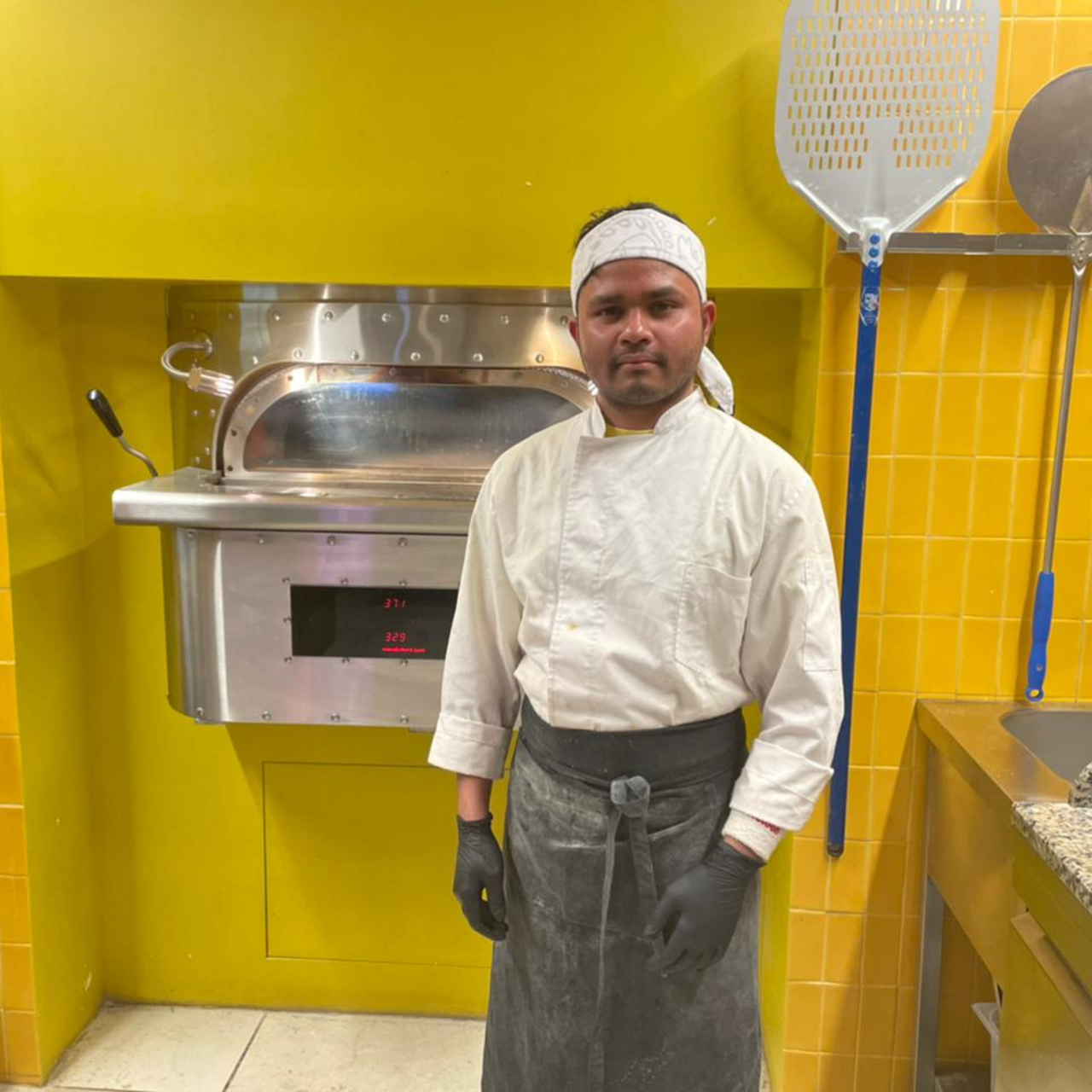 Parwan standing in front of his pizza oven